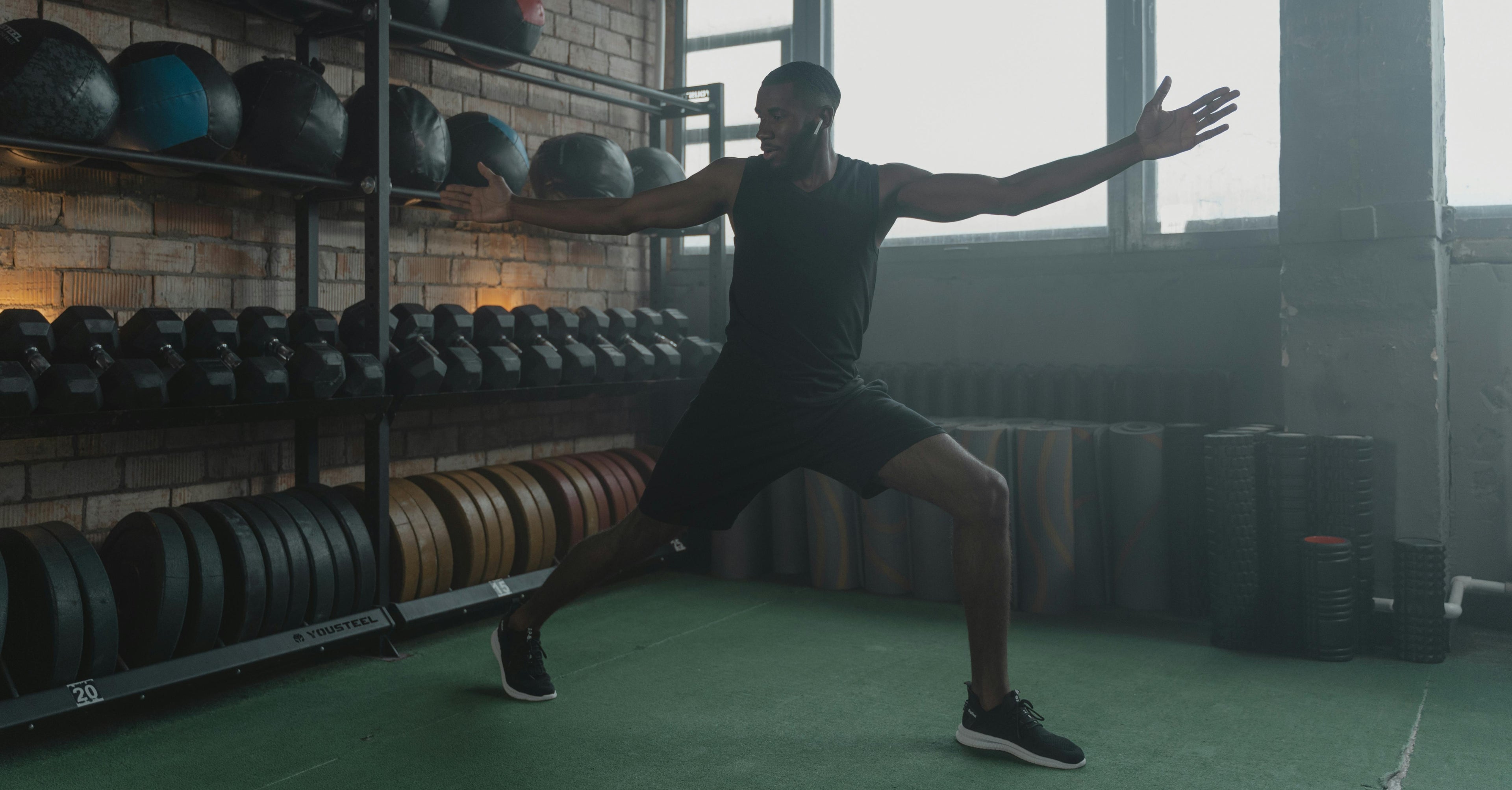 Person performing a squat exercise in a gym setting with weights and exercise balls in the background.