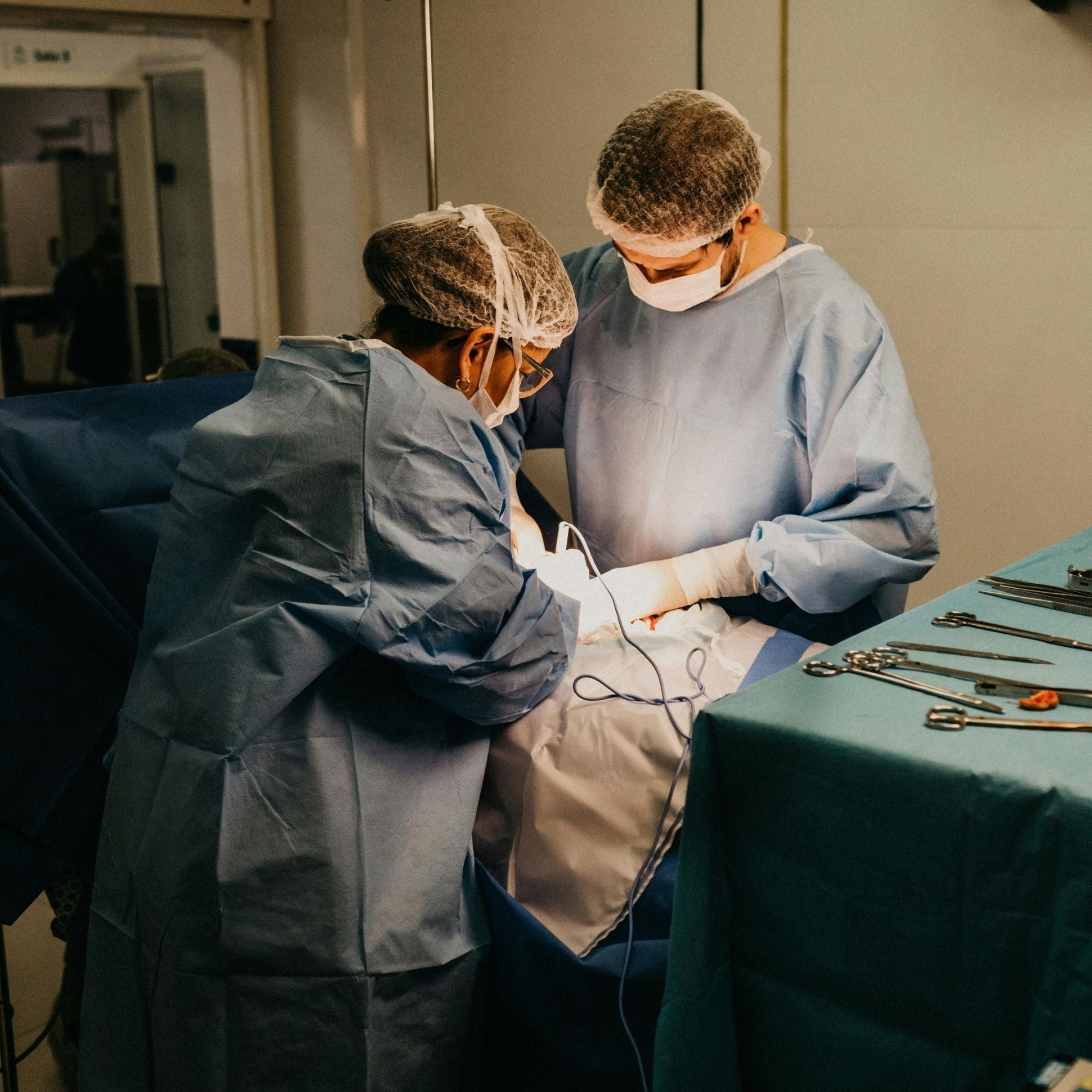 Two surgeons in an operating room with medical equipment.