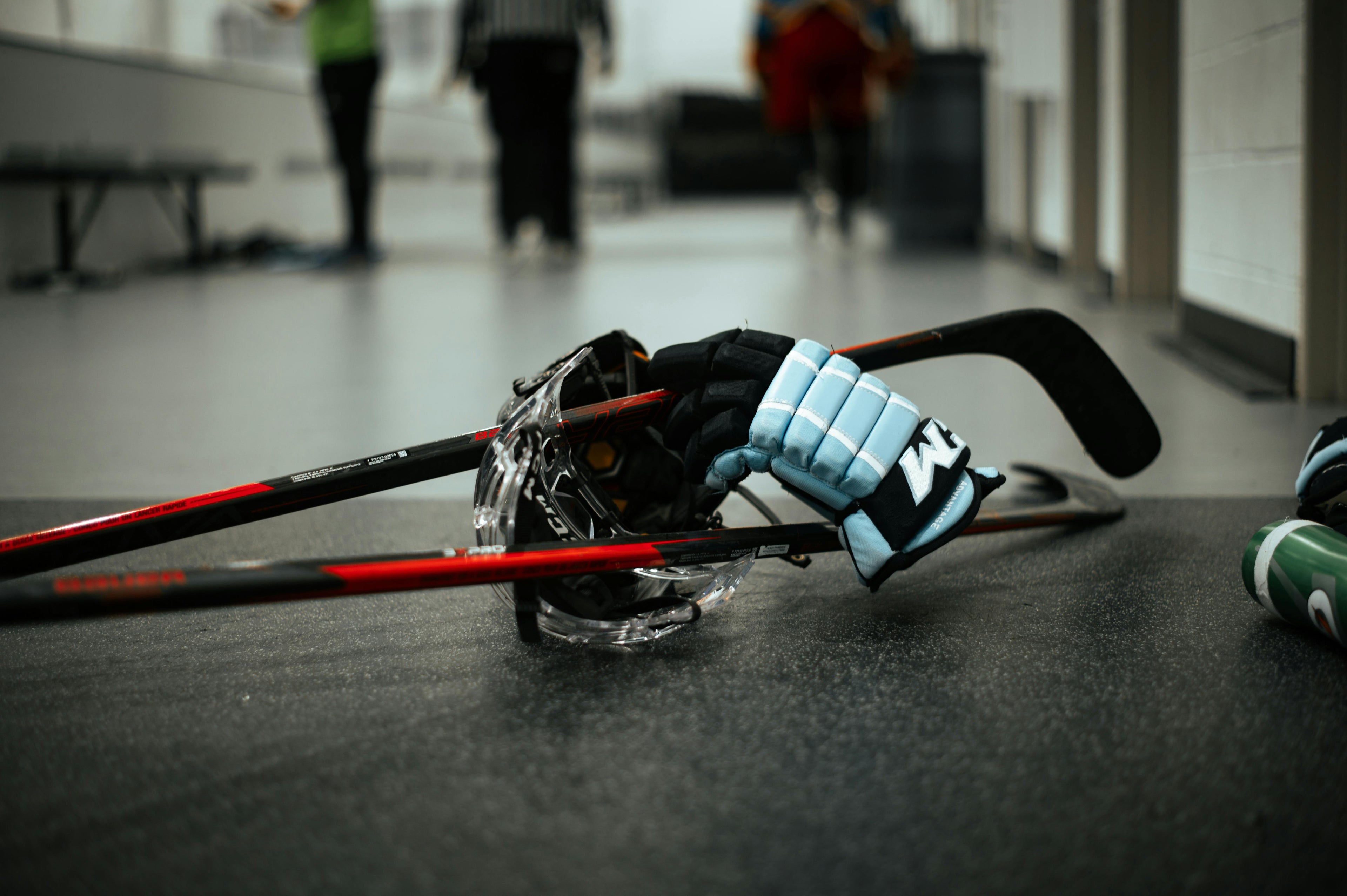 Close-up of hockey equipment on a surface with blurred people in the background