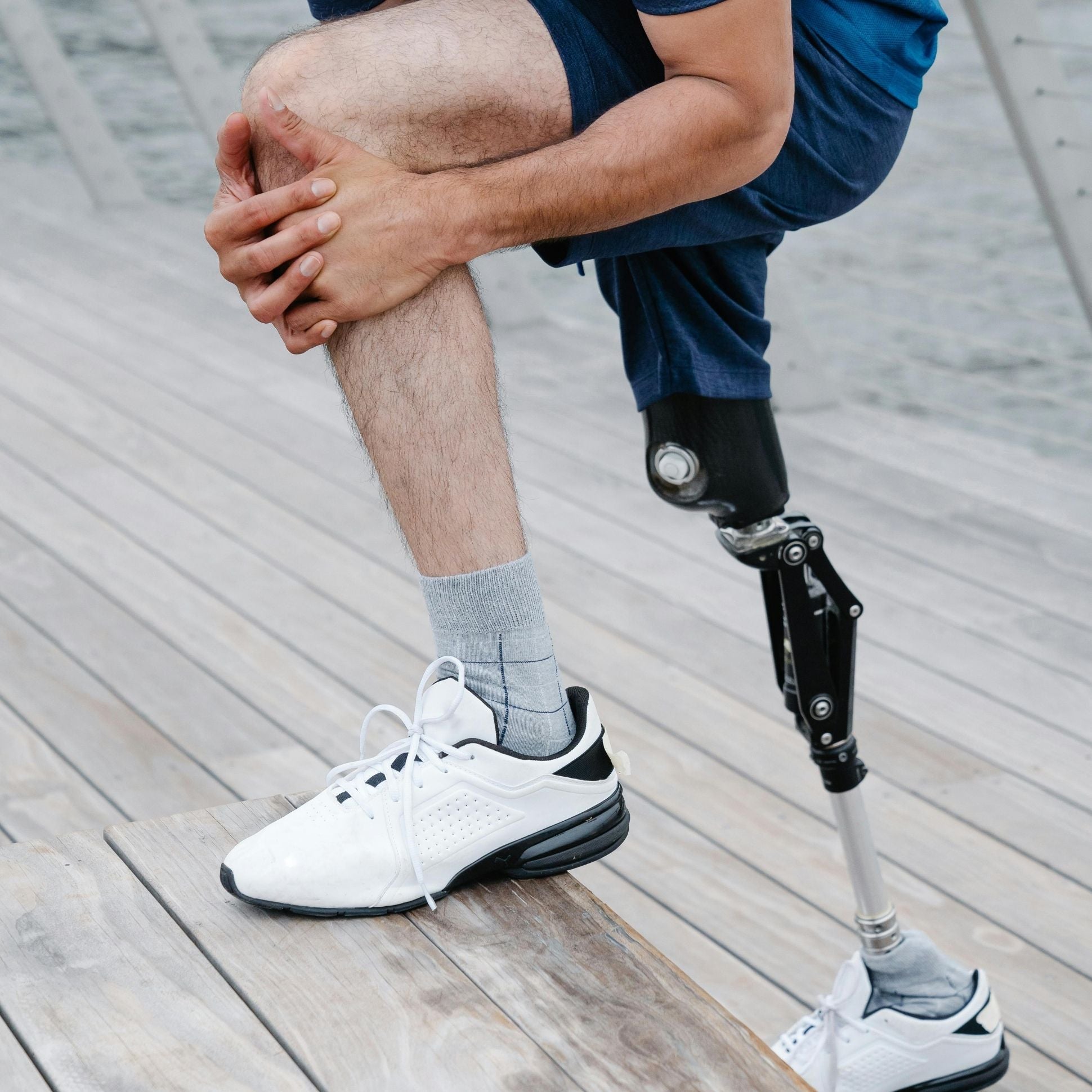 Person with a prosthetic leg sitting on a wooden surface