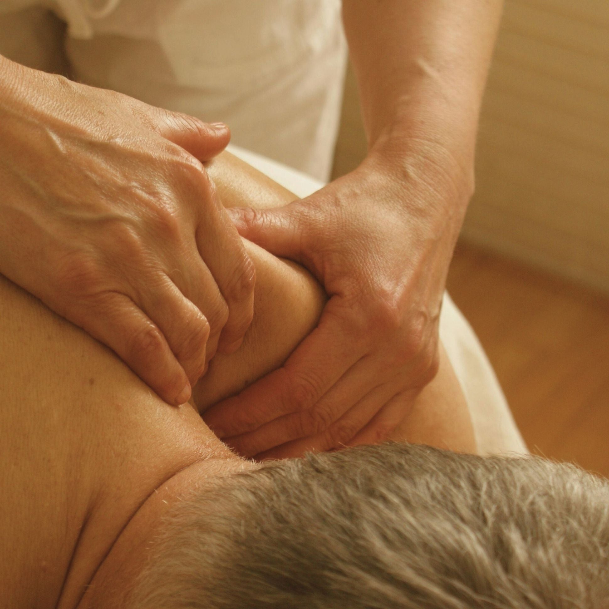 Close-up of a massage session with hands applying pressure to a person's leg.