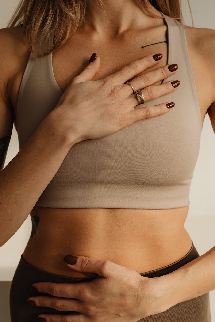Woman standing in a yoga pose with a hand on her stomach and hand over her heart